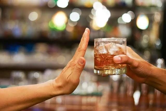 A hand declining a glass of alcohol